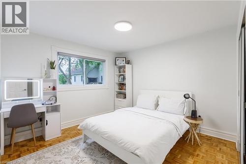 Bedroom with parquet wood-finish flooring, white walls, and a large window - 176 Riverbank Drive, Cambridge, ON 