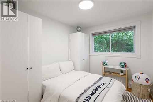 Bedroom featuring a large window with exterior tree canopy, two built-in wardrobes, and a flush-mount ceiling light fixture - 176 Riverbank Drive, Cambridge, ON 