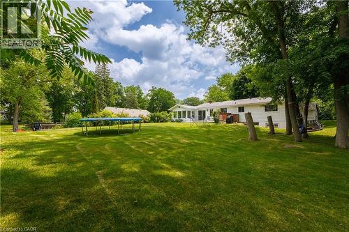 Expansive rear yard featuring mature trees, a manicured lawn, and a white siding home with a sunroom - 176 Riverbank Drive, Cambridge, ON 