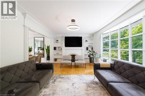 Spacious living area featuring large picture windows, parquet wood-finish flooring, a built-in fireplace with a mantel, and integrated shelving - 176 Riverbank Drive, Cambridge, ON 