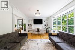 Spacious living area featuring large picture windows, parquet wood-finish flooring, a built-in fireplace with a mantel, and integrated shelving - 