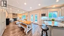 Open-concept living space featuring wood-finish flooring, recessed lighting, and a stone-clad fireplace - 