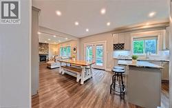 Open-concept interior featuring wood-finish flooring, recessed lighting, and a stone-faced fireplace - 