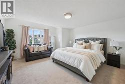 Spacious bedroom featuring light-toned carpeting, white painted walls, and a large window with ample natural light - 
