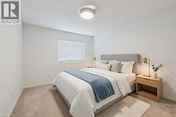 Bedroom with light neutral carpet flooring, a window with horizontal blinds, and a flush mount ceiling light fixture - 