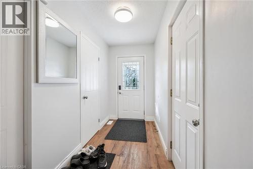 Entryway featuring warm wood-finish flooring, white paneled doors, and a decorative frosted glass front door - 765 Angler Way, Waterloo, ON 