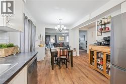 Open-concept kitchen and dining area featuring wood-finish flooring, white cabinetry, a built-in dishwasher, and a stainless steel refrigerator - 