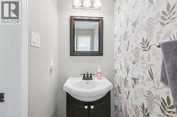Pedestal vanity with dark wood-finish cabinetry, white ceramic sink, and dark bronze faucet - 