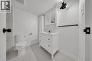 Bathroom featuring a white vanity with integrated sink, coordinating wall cabinet, white toilet, and marble-look tile flooring - 3085 Kingsway Drive Unit# 21, Kitchener, ON 