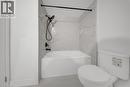 Bathroom featuring a white bathtub, white toilet, and white tile surround with gray veining - 3085 Kingsway Drive Unit# 21, Kitchener, ON 