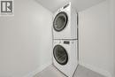 Dedicated laundry area featuring a stacked washer and dryer, contemporary white baseboards, and light-toned tile flooring - 3085 Kingsway Drive Unit# 21, Kitchener, ON 