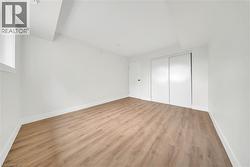 Bright interior room featuring light wood-finish flooring, white walls, and white baseboards - 