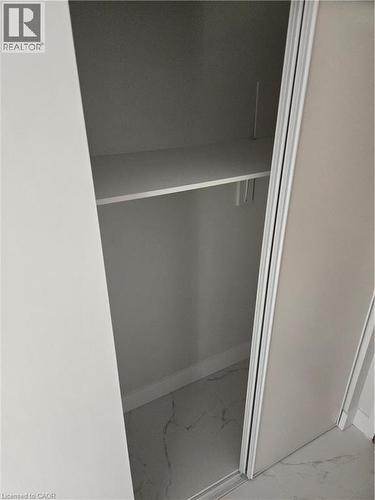Integrated closet with sliding panel doors, a single fixed shelf, and a marble-look floor - 3085 Kingsway Drive Unit# 21, Kitchener, ON 