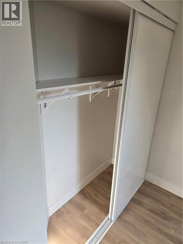 Built-in closet featuring sliding doors, integrated shelf, clothes rod, and wood-finish flooring - 3085 Kingsway Drive Unit# 21, Kitchener, ON 
