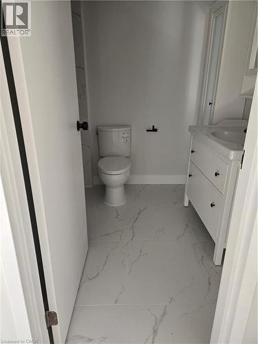 Powder room featuring white vanity with integrated sink, contemporary toilet, and large format marble-look floor tiles - 3085 Kingsway Drive Unit# 21, Kitchener, ON 