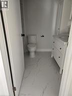 Powder room featuring white vanity with integrated sink, contemporary toilet, and large format marble-look floor tiles - 