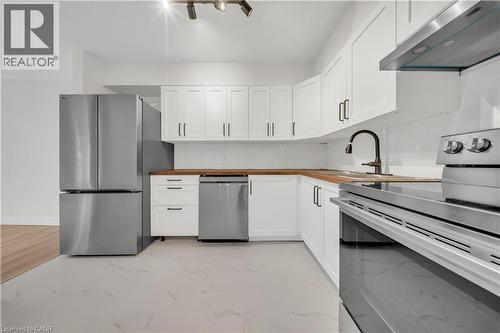 Modern kitchen featuring white shaker cabinetry, stainless steel appliances, wood-finish countertops, and white subway tile backsplash - 3085 Kingsway Drive Unit# 21, Kitchener, ON 