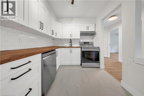 Modern kitchen featuring white shaker cabinetry, wood-finish countertops, and a white subway tile backsplash - 3085 Kingsway Drive Unit# 21, Kitchener, ON 