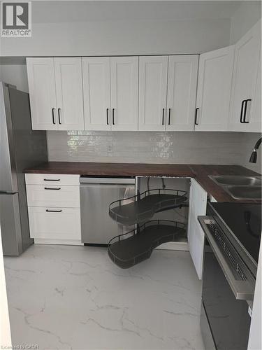 Contemporary kitchen featuring white shaker cabinetry, dark wood-finish countertops, and a white subway tile backsplash - 3085 Kingsway Drive Unit# 21, Kitchener, ON 