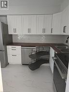 Contemporary kitchen featuring white shaker cabinetry, dark wood-finish countertops, and a white subway tile backsplash - 