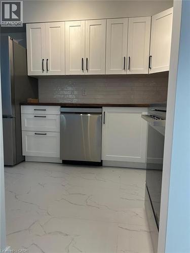 Contemporary kitchen featuring white shaker cabinetry with black hardware, wood-finish countertops, and a subway tile backsplash - 3085 Kingsway Drive Unit# 21, Kitchener, ON 