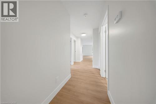 Bright hallway featuring light wood-finish flooring, white baseboards, and flush-mount ceiling lighting - 3085 Kingsway Drive Unit# 21, Kitchener, ON 