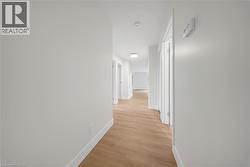 Bright hallway featuring light wood-finish flooring, white baseboards, and flush-mount ceiling lighting - 
