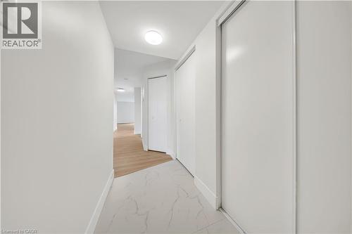 Hallway featuring white walls, recessed ceiling lighting, a white ceiling, light wood-finish flooring, and white sliding closet doors - 3085 Kingsway Drive Unit# 21, Kitchener, ON 