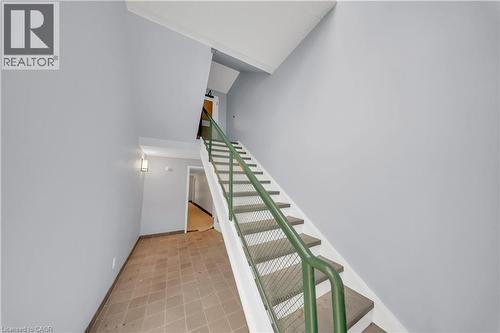 Stairwell featuring a green metal handrail with cable infill, white risers, and neutral-toned treads - 3085 Kingsway Drive Unit# 21, Kitchener, ON 