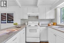 Bright kitchen with white cabinetry, light countertops, and a full suite of white appliances - 