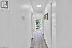 Hallway with light wood-finish flooring, recessed ceiling lighting, and white baseboards - 