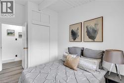 Bedroom featuring light-toned wood-finish flooring, white walls, and a white plank ceiling - 