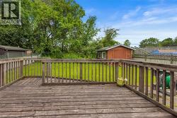 Wood-finish deck with railing overlooking a green lawn - 