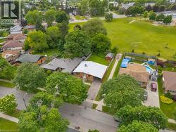 Single-story brick residence featuring a covered carport, mature front yard trees, and a paved driveway - 