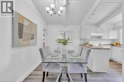 Dining area featuring a glass-top table, upholstered chairs, and wood-finish flooring - 