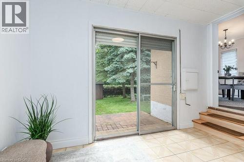 Sliding glass door opening to a brick patio and verdant backyard - 139 Mackay Crescent, Waterloo, ON 