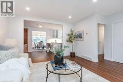Open-concept living area featuring rich wood-finish flooring, recessed lighting, and crisp white walls - 