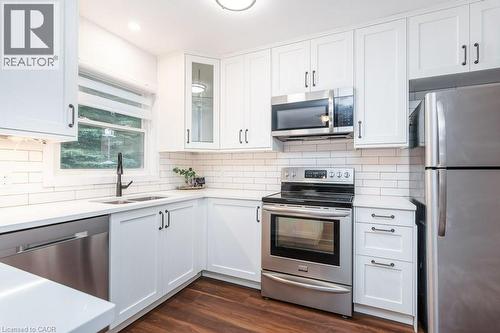Kitchen featuring white shaker-style cabinetry, stainless steel appliances, white subway tile backsplash, and dark wood-finish flooring - 139 Mackay Crescent, Waterloo, ON - Indoor Photo Showing Kitchen With Upgraded Kitchen