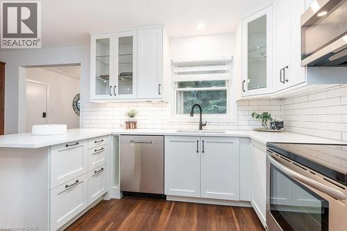 Modern kitchen featuring white shaker-style cabinetry, stainless steel appliances, white subway tile backsplash, and wood-finish flooring - 139 Mackay Crescent, Waterloo, ON - Indoor Photo Showing Kitchen With Upgraded Kitchen