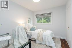 Light-filled room featuring a single window with blinds, wood-finish flooring, a neutral wall color, and white trim - 