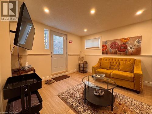 Living area featuring wood-finish flooring, recessed ceiling lighting, a white panel door with frosted glass, and a window with a roller shade - 110 Marl Meadow Drive Unit# B, Kitchener, ON 