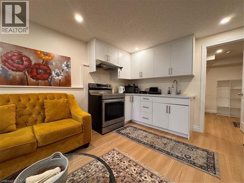 Kitchen area featuring white cabinetry, a stainless steel range, and a coordinating range hood - 110 Marl Meadow Drive Unit# B, Kitchener, ON 