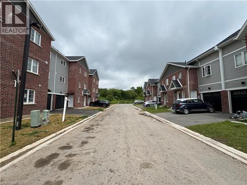 Contemporary townhomes featuring brick and siding exteriors, individual garages with black doors, and white-trimmed windows - 113 Highriver Trail Unit# Main, Welland, ON - Outdoor
