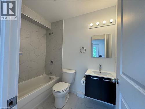 Bathroom featuring a white bathtub with chrome fixtures, a toilet, and a vanity with a white basin sink and dark cabinetry - 119 Highriver Trail Unit# Main, Welland, ON - Indoor Photo Showing Bathroom