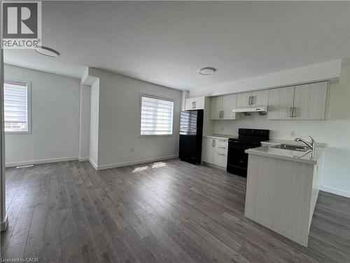 Modern kitchen with light wood-finish cabinetry, black appliances, and a peninsula with a stainless steel sink - 133 Highriver Trail Unit# Main, Welland, ON 