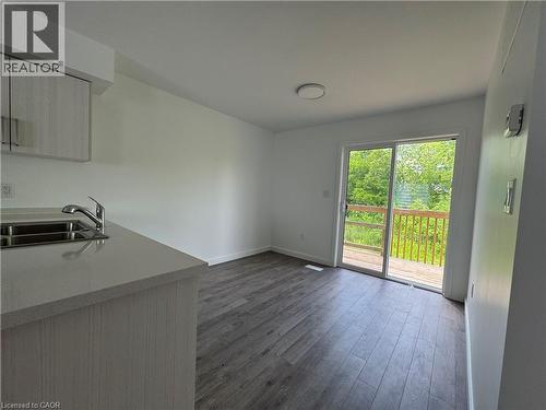 Contemporary kitchen area featuring a stainless steel double sink, light grey countertop, and light wood-grain cabinetry - 133 Highriver Trail Unit# Main, Welland, ON 