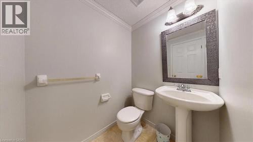 Pedestal sink with chrome fixtures, framed mirror, two-bulb vanity light, and a toilet - 980 Creekside Drive, Waterloo, ON - Indoor Photo Showing Bathroom