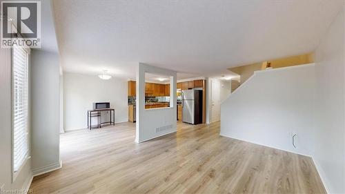 Open-concept living space featuring wood-finish flooring, white walls, and a staircase with a white railing - 980 Creekside Drive, Waterloo, ON - Indoor