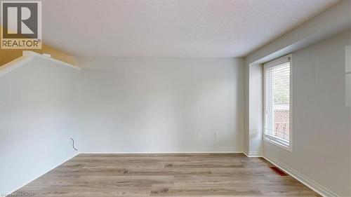 Spacious room featuring light wood-finish flooring, a bright window with horizontal blinds, and a neutral wall color - 980 Creekside Drive, Waterloo, ON - Indoor Photo Showing Other Room