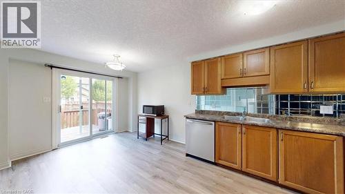 Kitchen area featuring wood-finish flooring, light wood cabinetry, and a mirrored backsplash - 980 Creekside Drive, Waterloo, ON - Indoor Photo Showing Kitchen With Double Sink